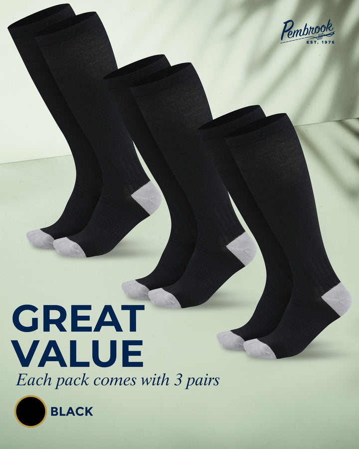 Three pairs of black knee-high socks with white toes and heels on a light green background, featuring the brand &