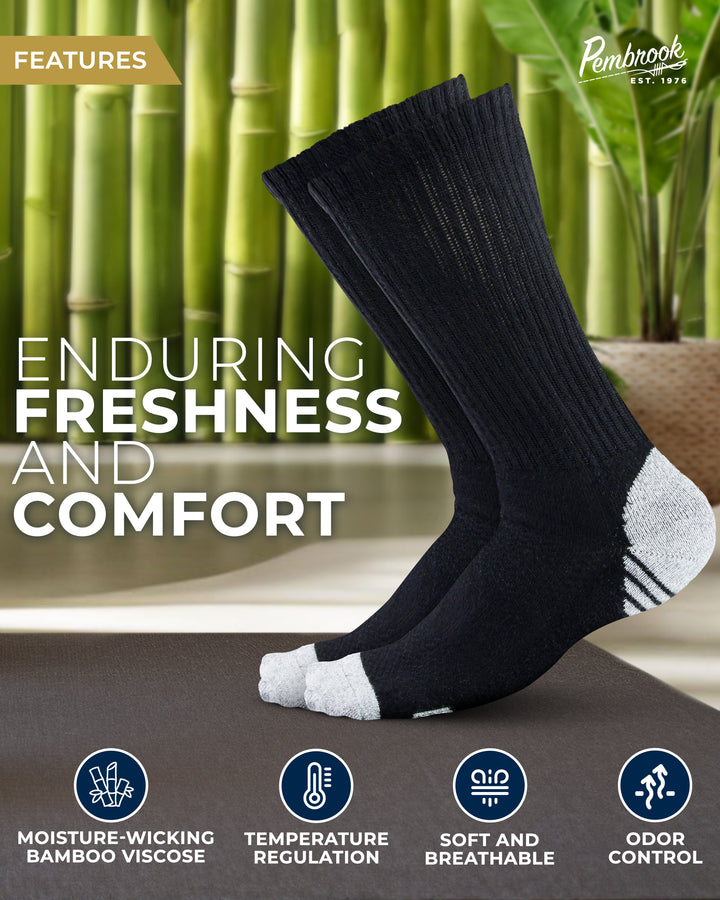 Black socks with white toes and heels on a gray surface with bamboo plants in the background, featuring text about enduring freshness and comfort.